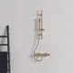 Brausethermostat in gebürstetem Gold von Ideal Standard, mit zwei Pin-Griffen. An der Wand montiert, präsentiert sich das Produkt mit klaren Linien und minimalistischer Form.